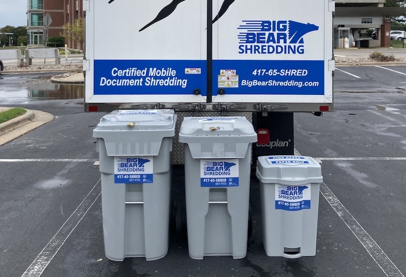 The Big Bear Shredding truck parked in a parking lot with the three various sized Collection Bins lined up from largest to smallest behind it.